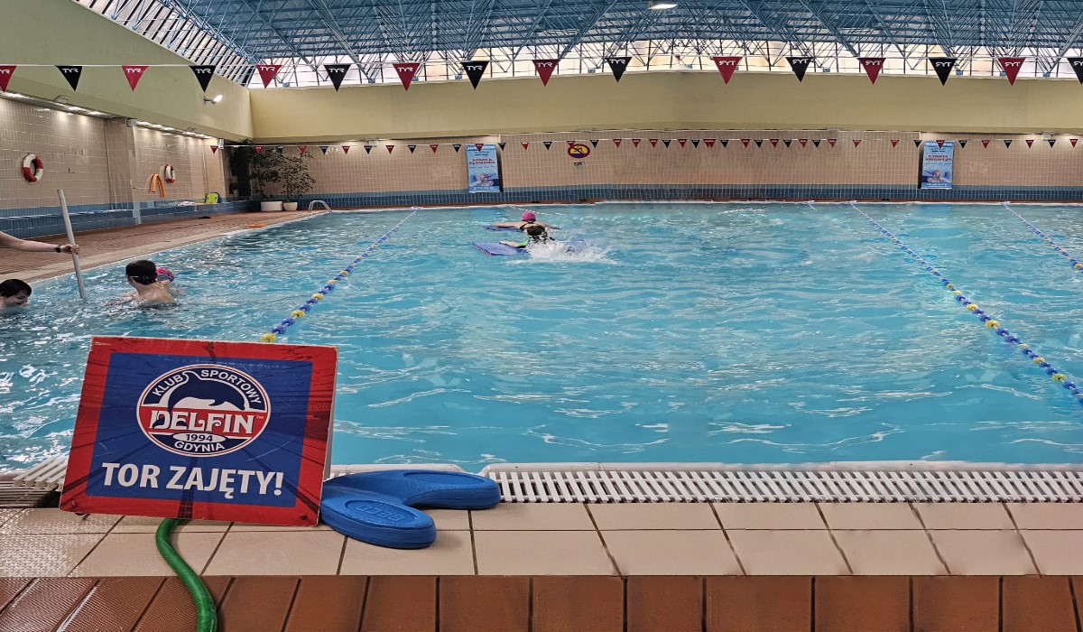 Fotografia z akcji "BFI Baby Sharks" na kt&oacute;rej widać pływającą młodzieć pod okiem instruktora ze szkoły pływackiej Delfin