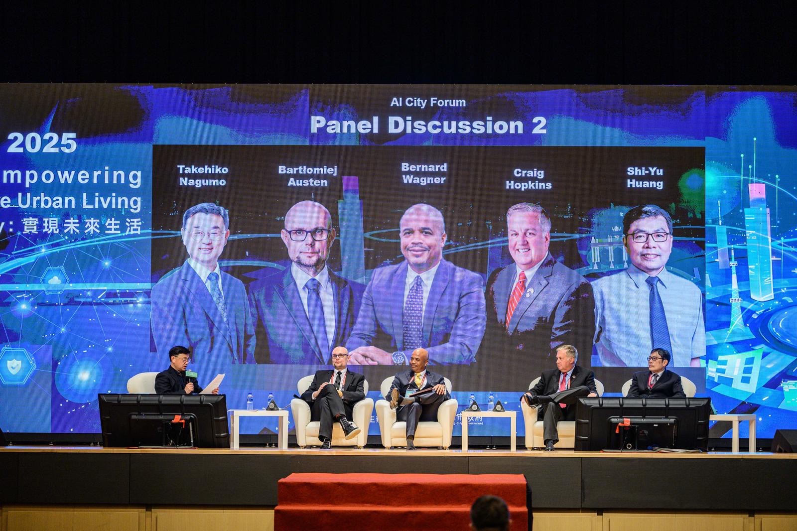 Scena dużej sali konferencyjnej, na scenie fotele, w kt&oacute;rych siedzi kilku prelegent&oacute;w, w tle duży ekran z wyświetlanymi zdjęciami i nazwiskami gości