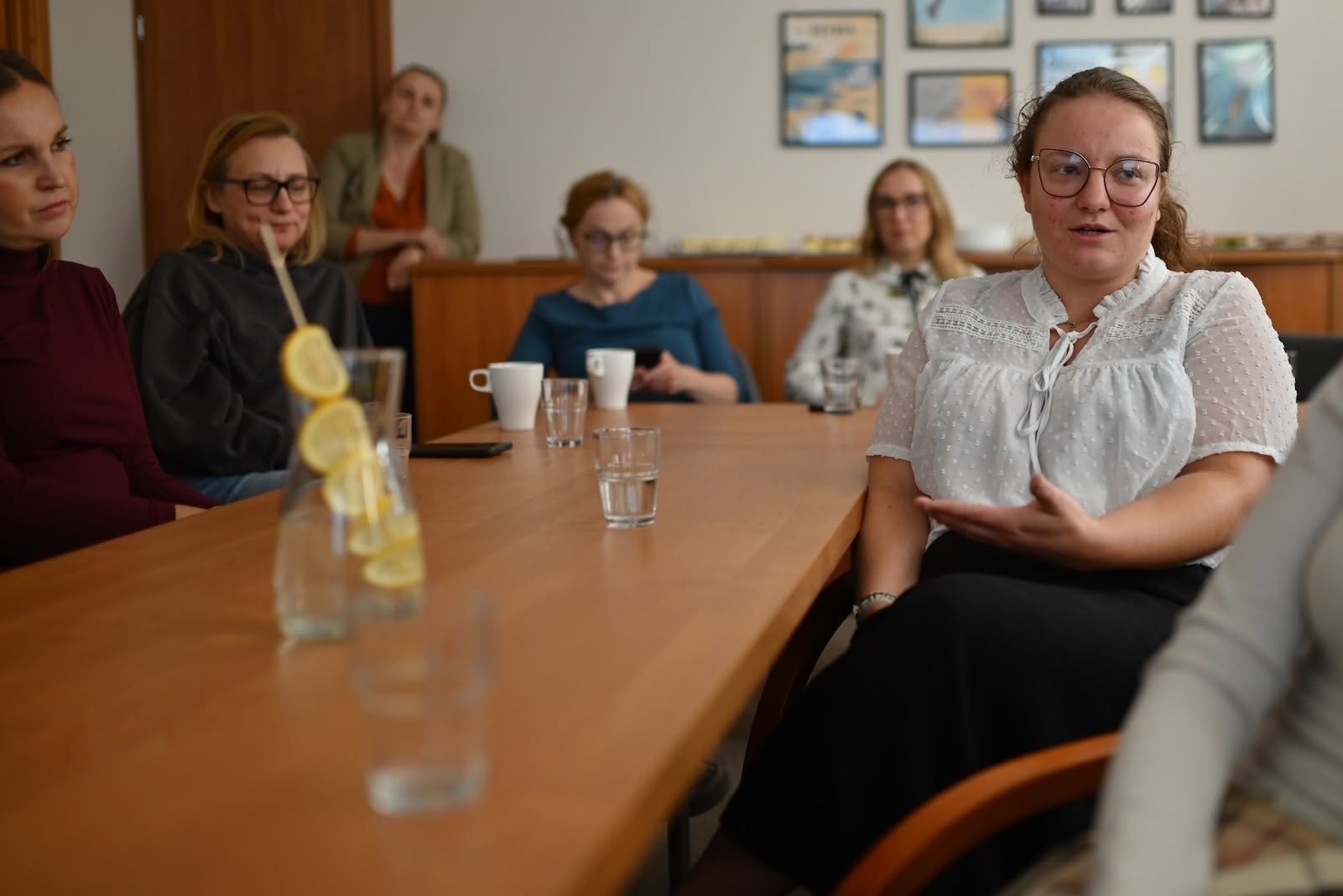 Młoda kobieta przemawiająca do pozostałych uczestnik&oacute;w spotkania