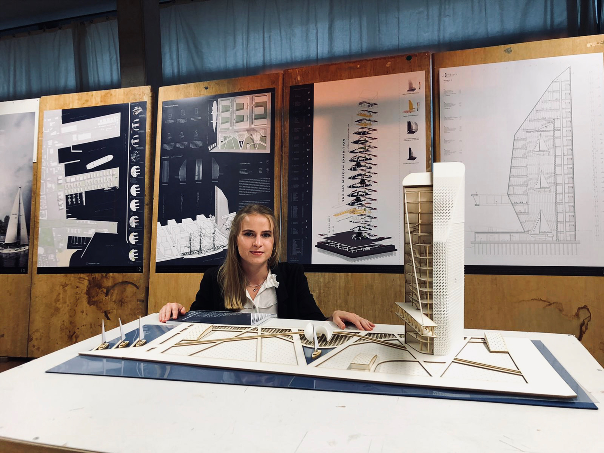 Agata Morawczyńska, autorka projektu Muzeum Żeglarstwa, podczas obrony pracy magisterskiej. Przed autorką znajduje się makieta budynku; z tyłu widoczne są plansze projektu. // fot. mat. prasowe