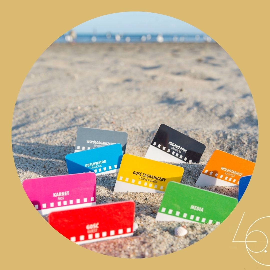 R&oacute;żnego rodzaju akredytacje festiwalowe włożone w piasek na plaży // materiały prasowe