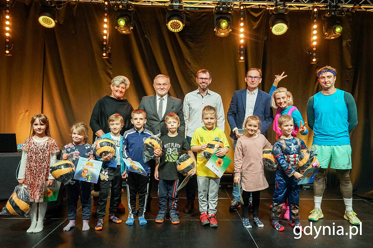 Na scenie grupa dzieci z nagrodami i dorosłych.