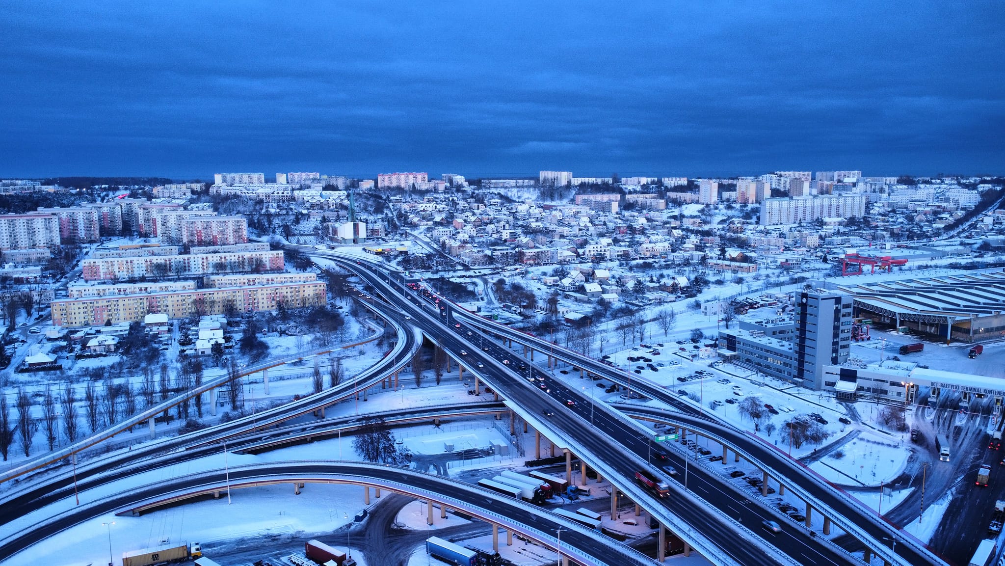 Lotnicze zdjęcie Gdyni, widoczna Estakada Kwiatkowskiego, łącznice, zabudowania, część Portu Gdynia, zima, śnieg, wiecz&oacute;r