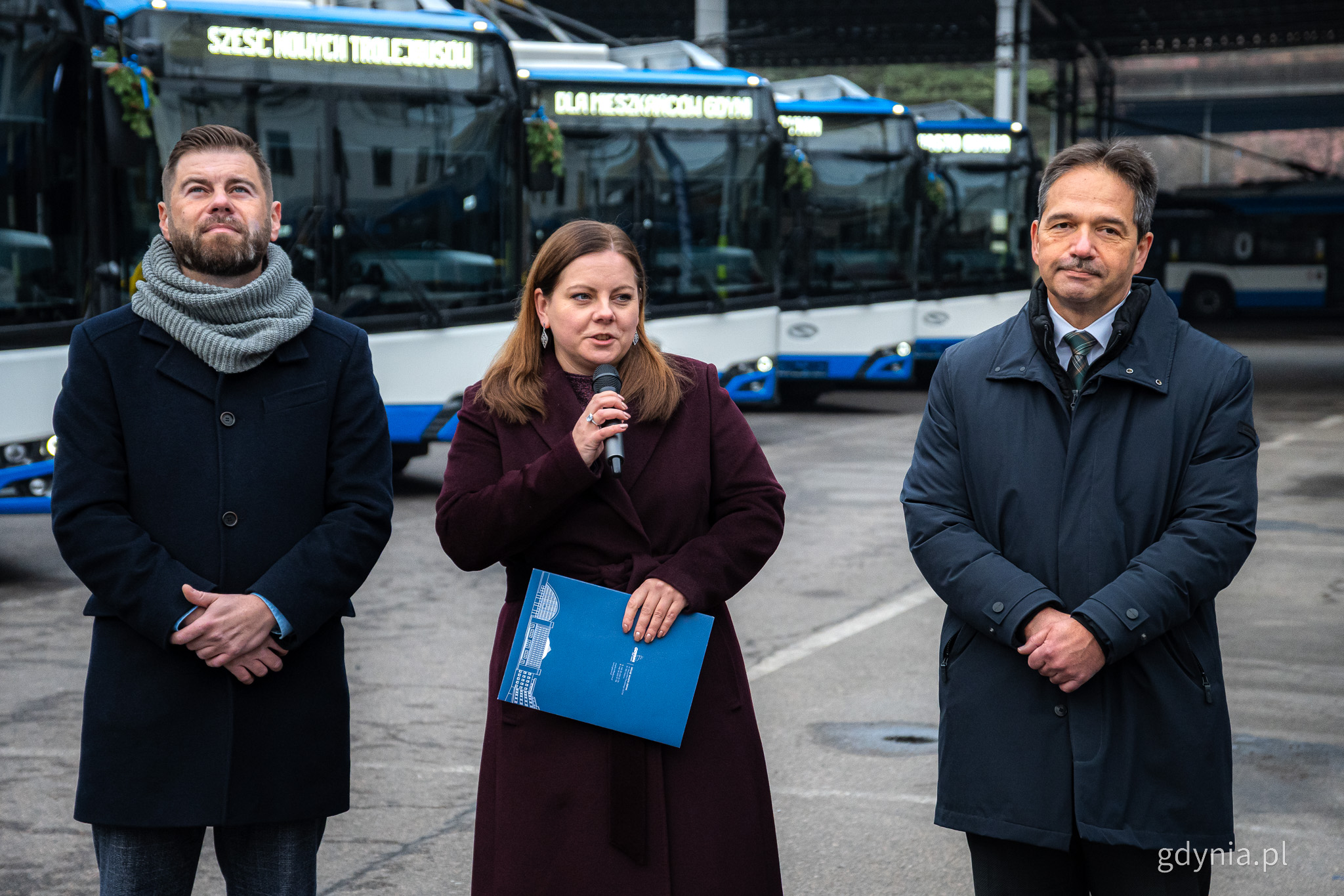 Marcin Połom, Aleksandra Kosiorek i Hubert Kołodziejski przemawiają w bazie PKT, w tle nowe trolejbusy 