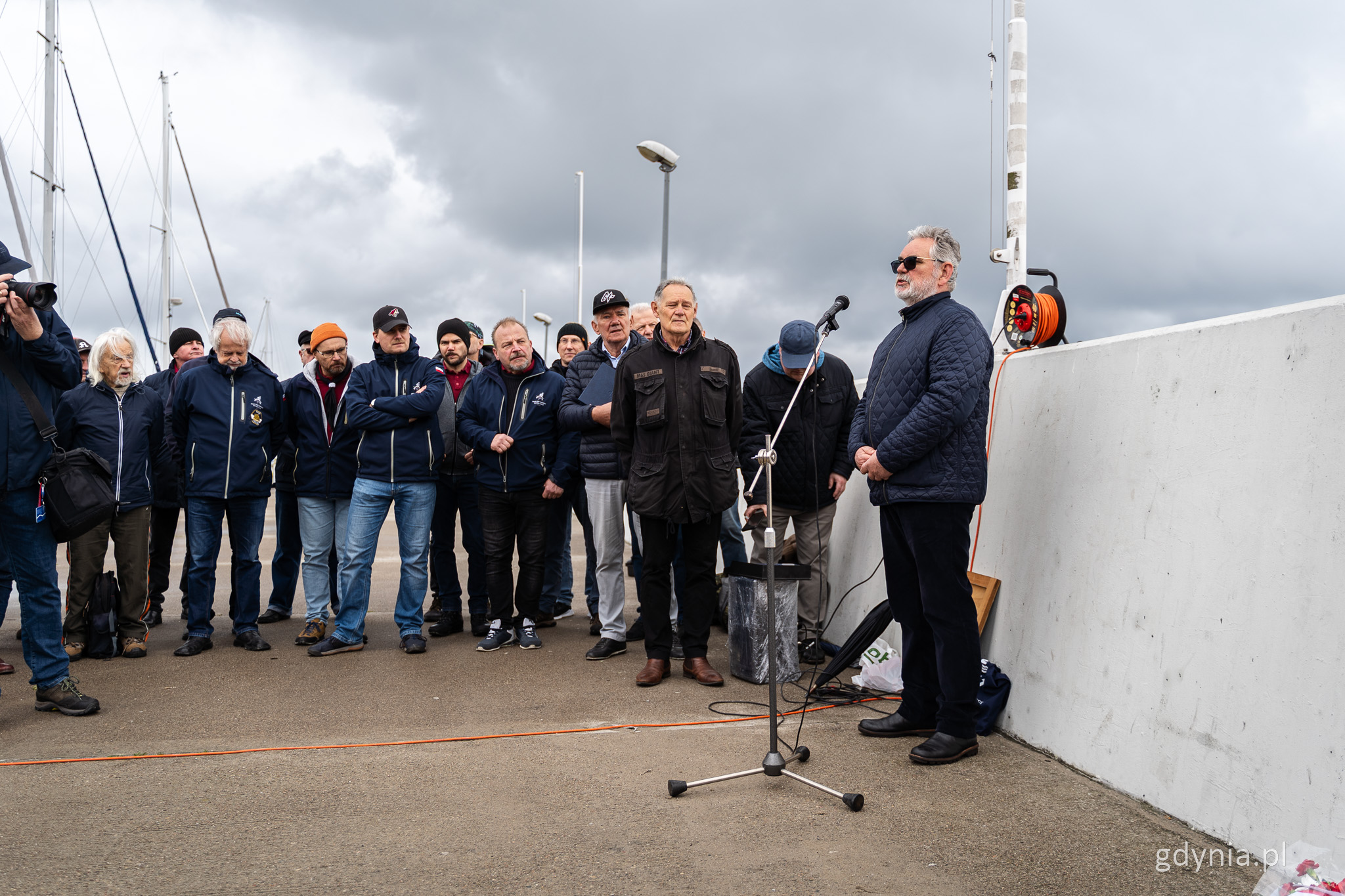 Falochron, nabrzeże w marinie w Gdyni, grupa os&oacute;b, przemawia przez mikrofon Janusz Sienkiewicz