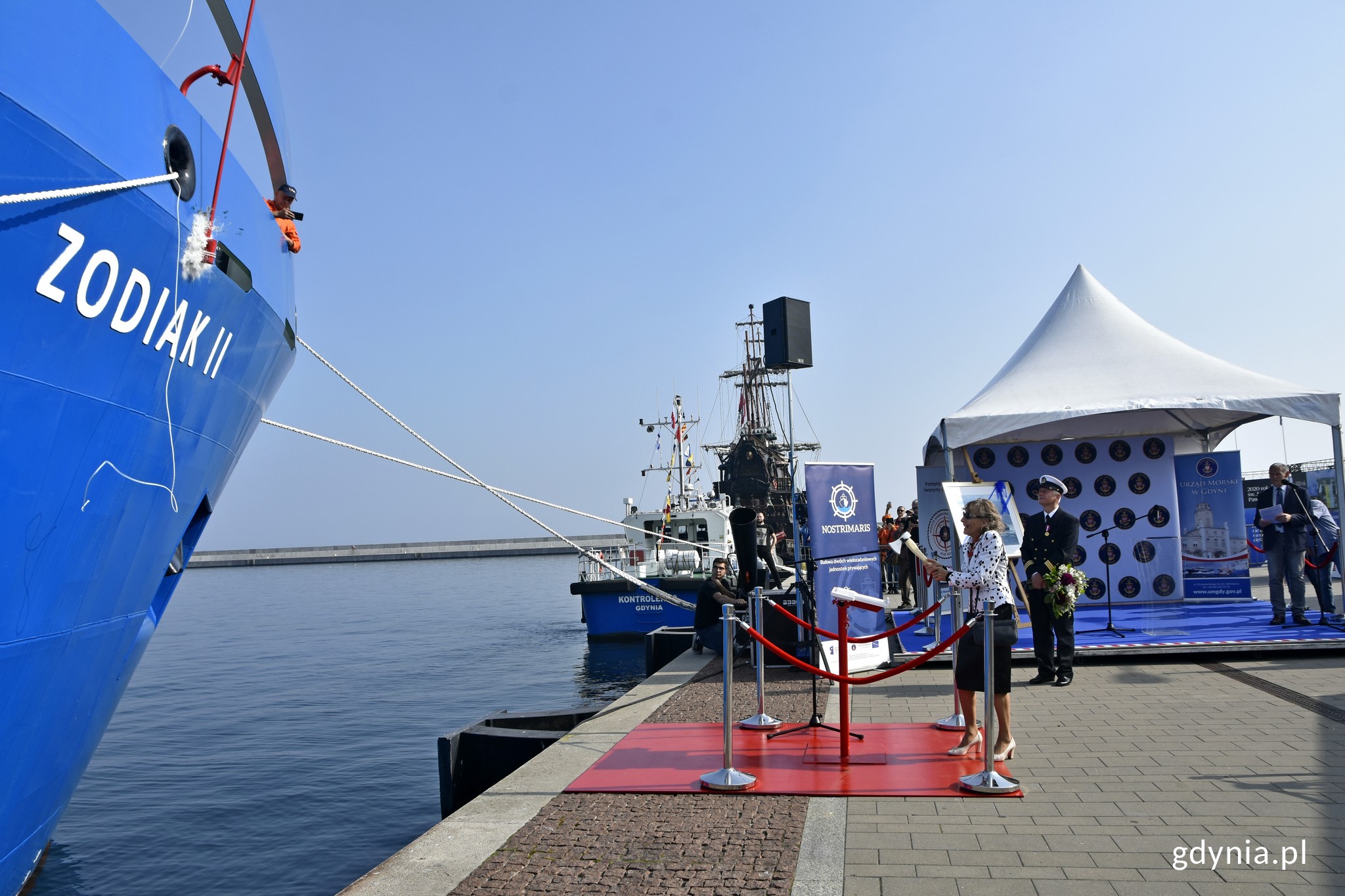 Mieczysława Piotrzkowska, matka chrzestna "Zodiaka II" rozbija butelkę o jego niebiski kadłub podczas uroczystości chrztu i podniesienia bandery na pokładzie statku // fot. Magdalena Czernek