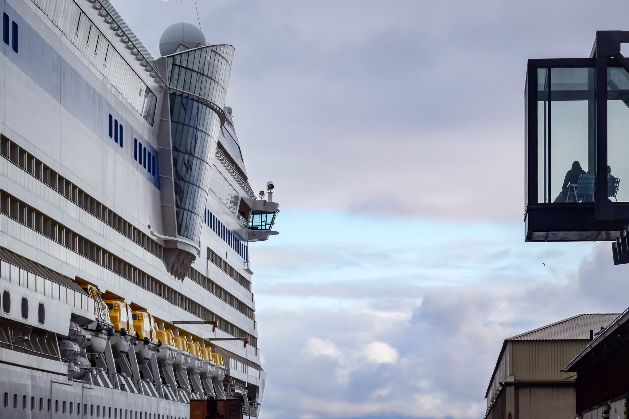 Port w Gdyni, burta statku wycieczkowego, widać kabiny, widać taras widokowy w Muzeum Emigracji, na kt&oacute;rym stoi krzesło