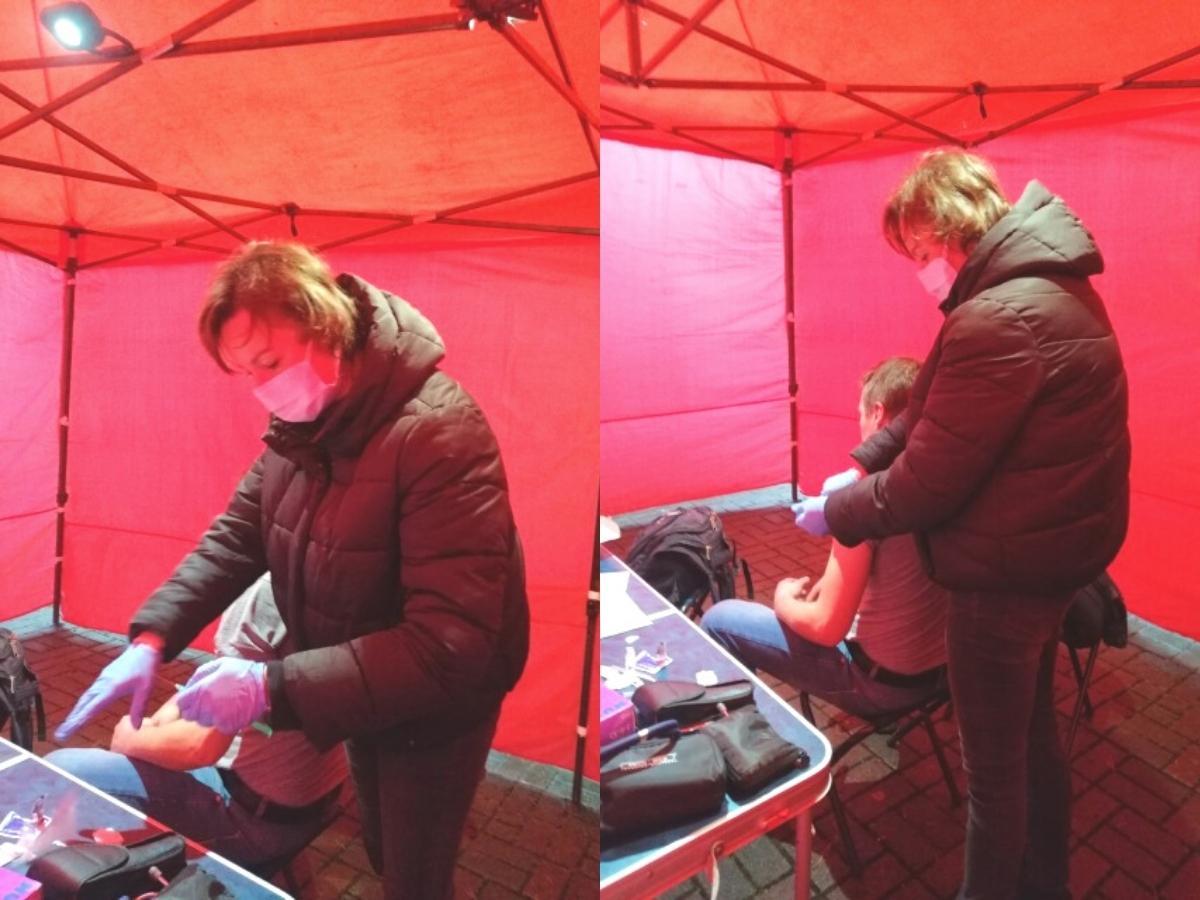 w dużym namiocie kobieta robi zastrzyk mężczyźnie