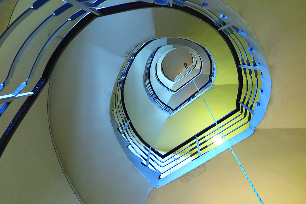 Dusza klatki schodowej w kamienicy przy ul. 10 Lutego 32. Widoczny układ serpentyny podkreślony ażurowymi, metalowymi balustradami z&nbsp;poręczą z drewna.