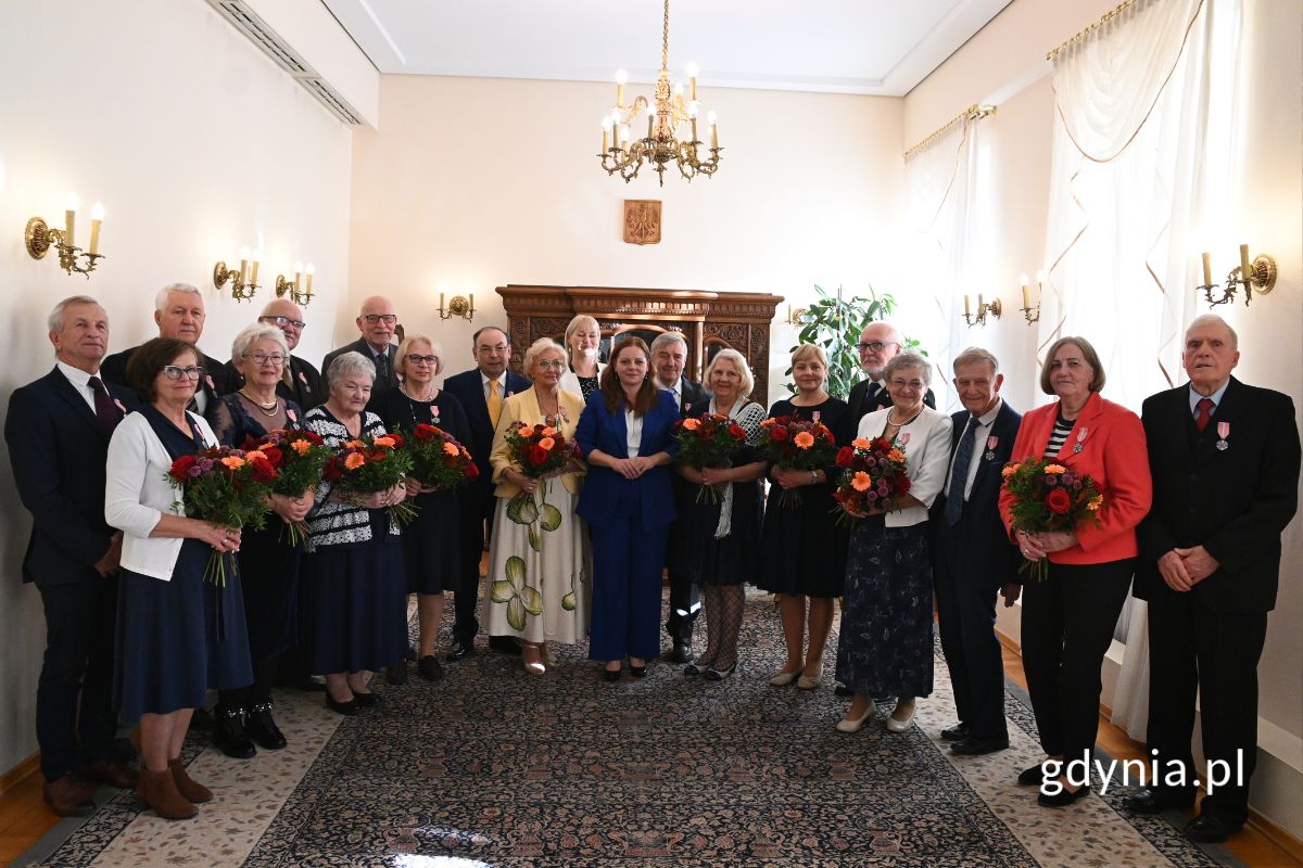Seniorzy stojący w eleganckiej sali