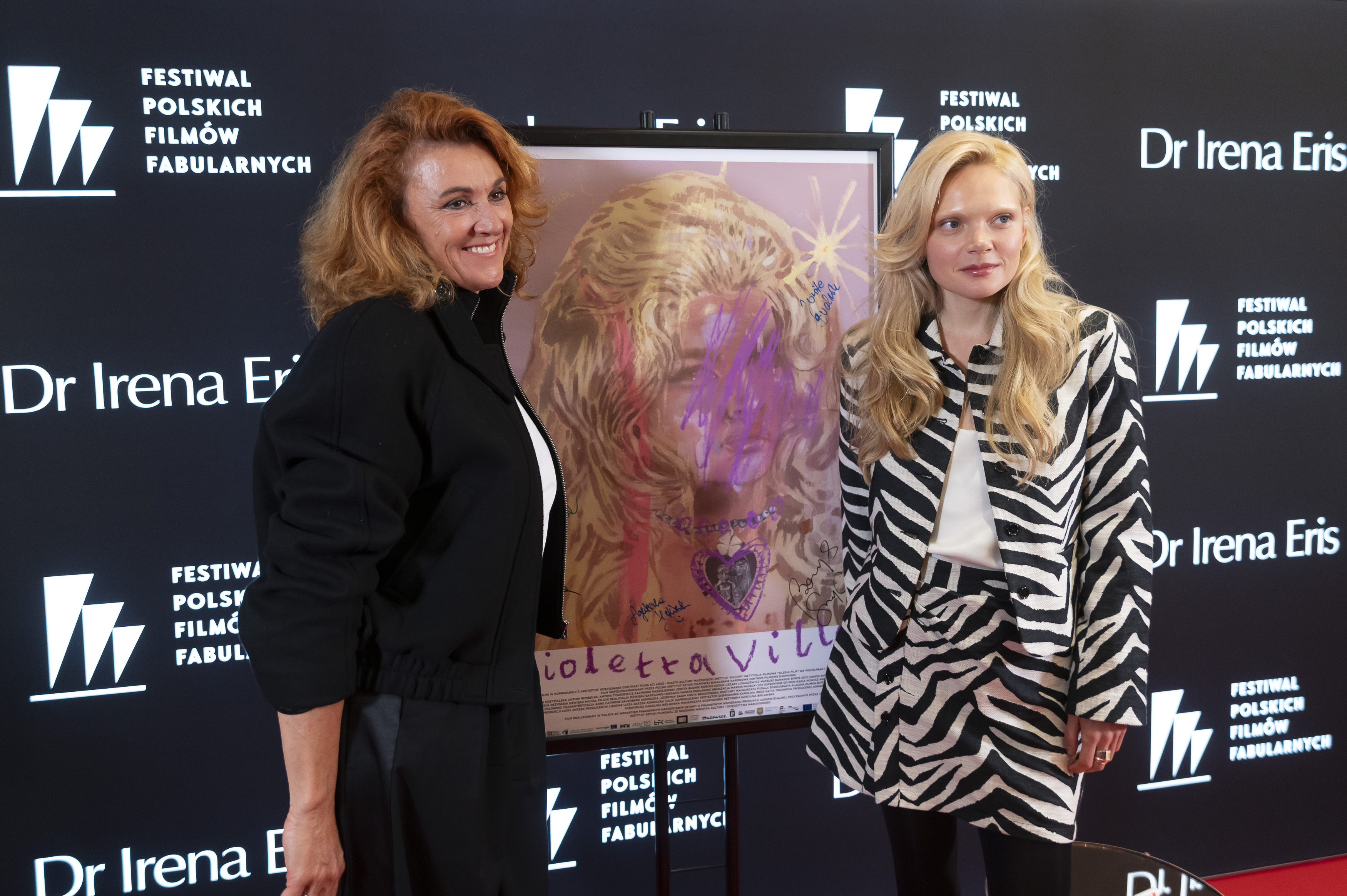 Dwie kobiety pozują do zdjęcia przy plakacie filmu "Violetta Villas"