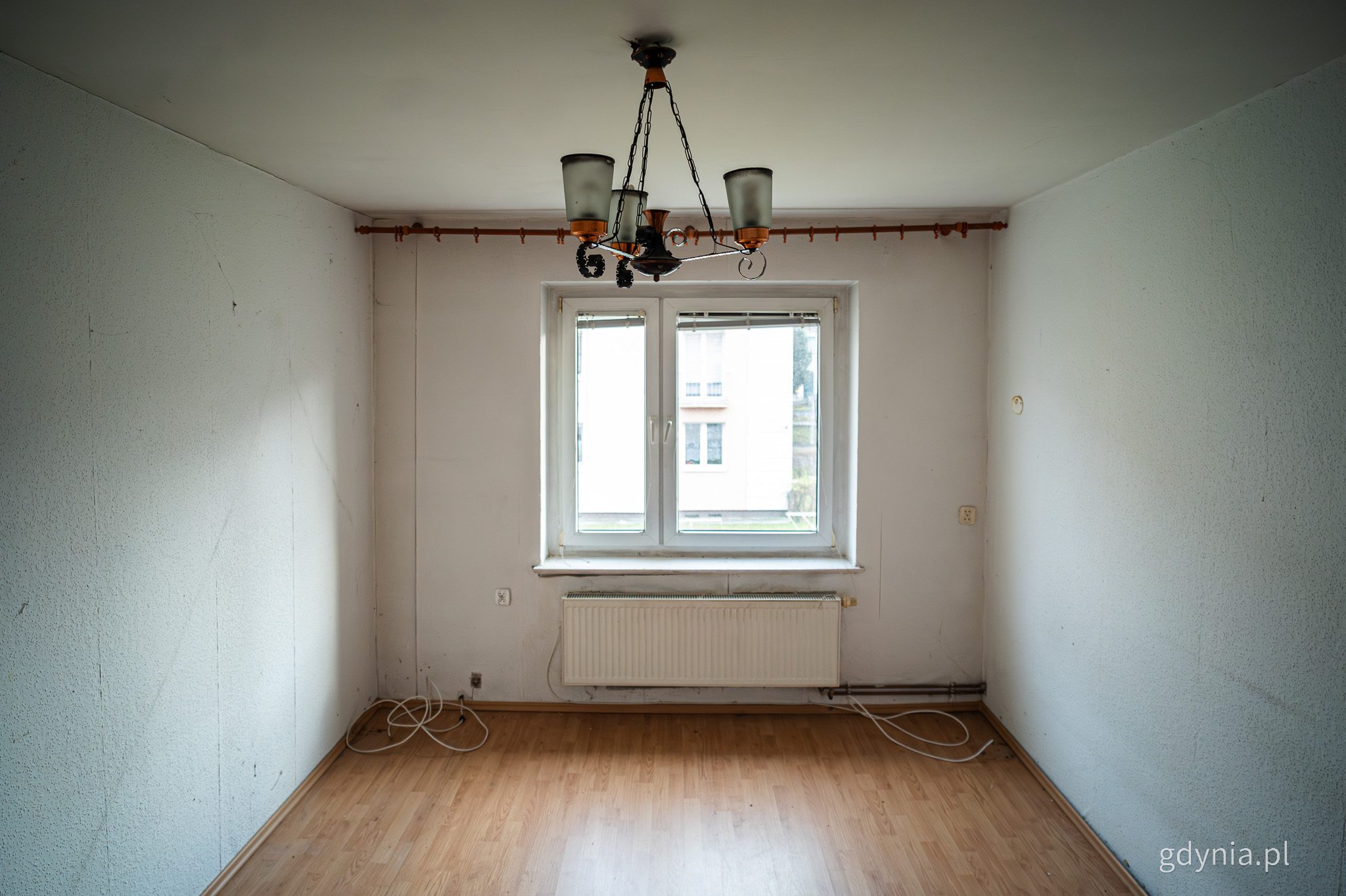 Puste pomieszczenie, widoczne okno, żyrandol, podłoga