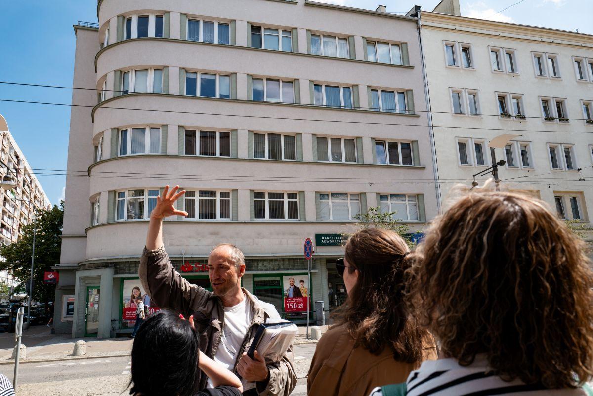 Grupa ludzi w centrum Gdyni ogląda budynku modernistyczne 