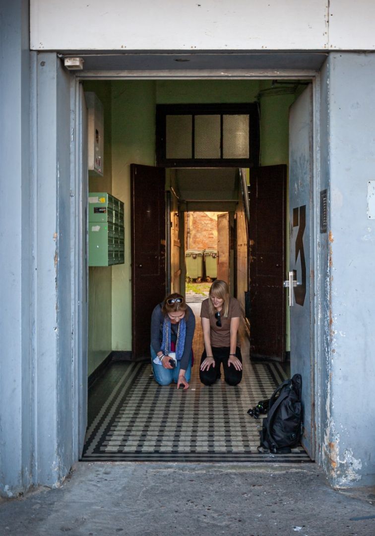 Zdjęcie archiwalne ze spaceru architektonicznego. Dwie kobiety klęczą na posadzce w jednej z gdyńskich kamienic // fot. Tomasz Lelito