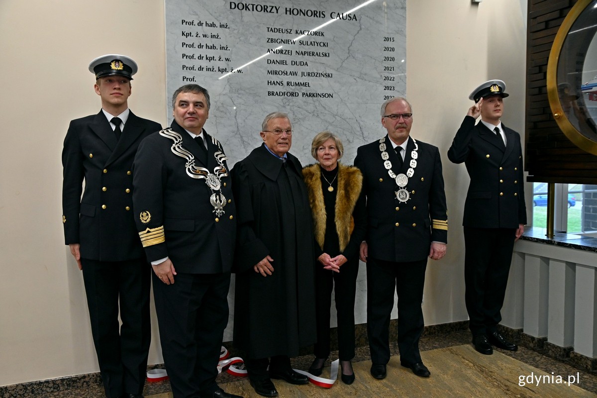 Od lewej: prof. dr hab. inż. kpt. ż. w. Adam Weintrit, rektor Uniwersytetu Morskiego w Gdyni, prof. Bradford Parkinson z małżonką oraz prof. dr hab. inż. Krzysztof Czaplewski przy tablicy informującej o doktorach honoris causa Uniwersytetu Morskiego (fot. Magdalena Czernek)