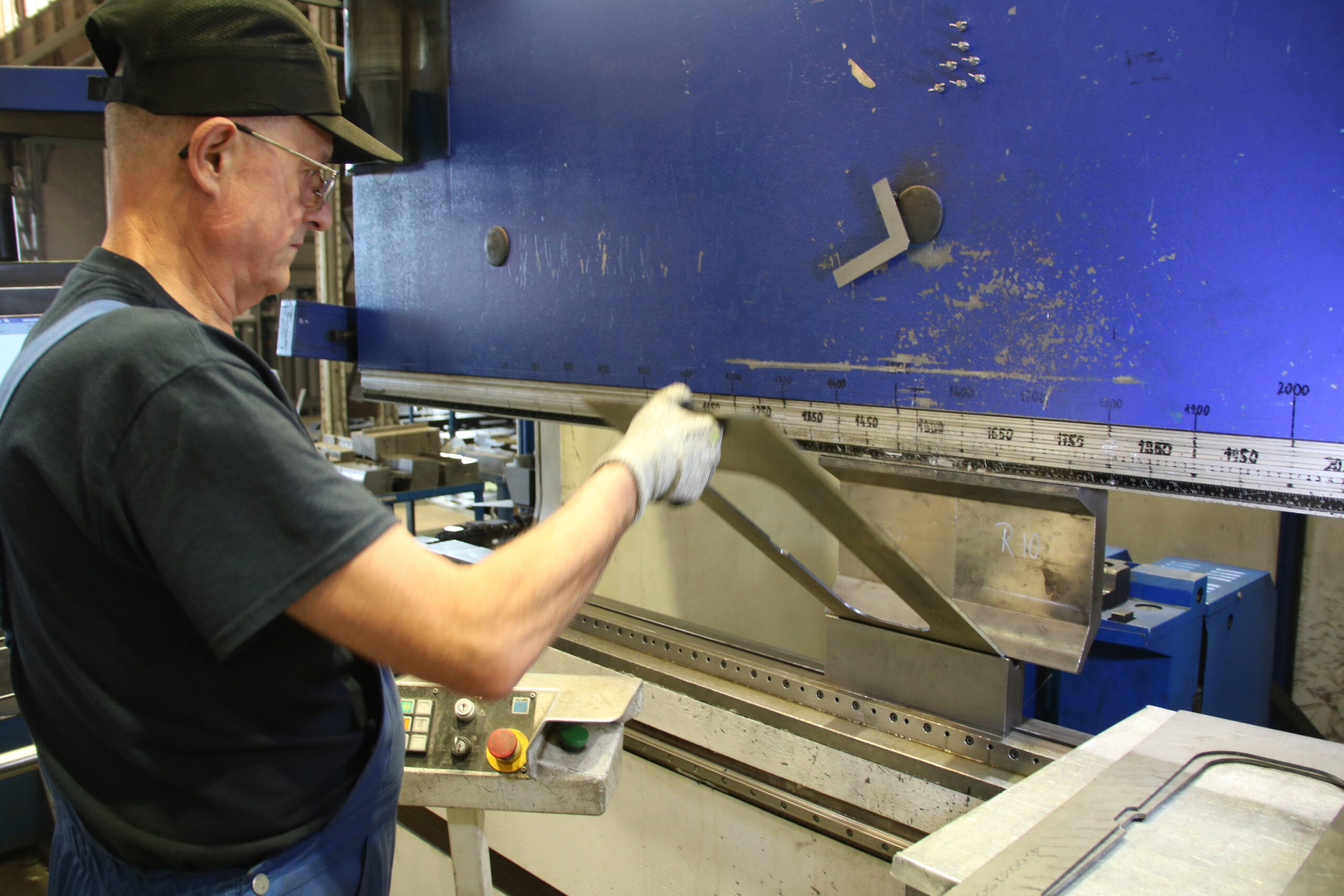 Mężczyzna na hali produkcyjnej przy maszynie.