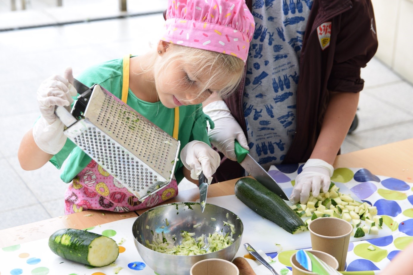 Warsztaty z kuchni ukraińskiej. Na zdjęciu dziewczynka uciera na tarce warzywa