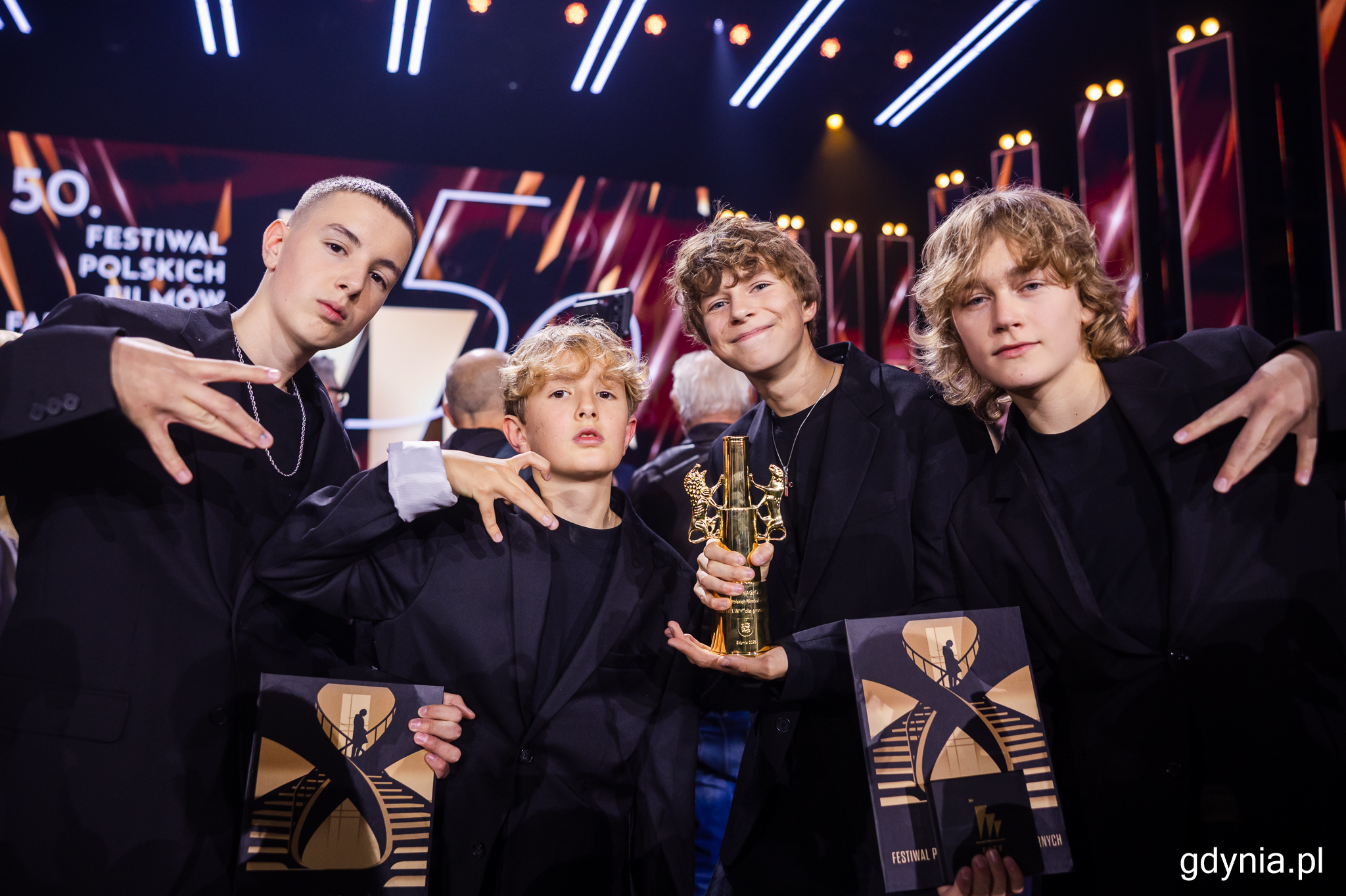 Gala 50. FPFF, scena, czterech chłopc&oacute;w pozuje do zdjęcia ze statuetką Złote Lwy