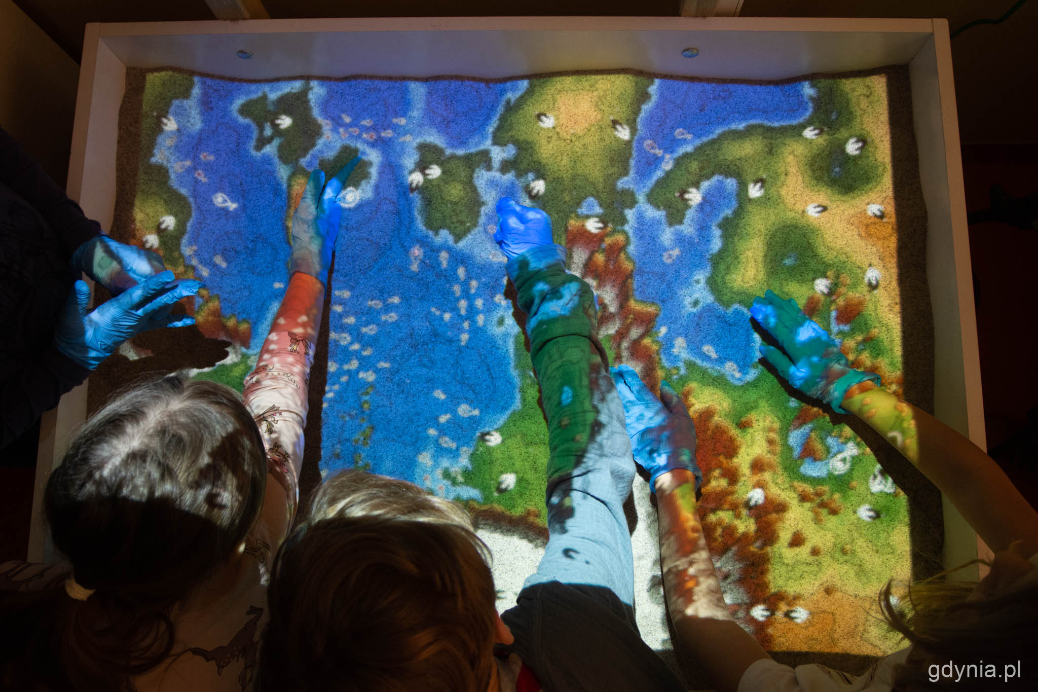 Interaktywna piaskownica w SP 44 w Gdyni. Na zdjęciu piaskownica widziana z g&oacute;ry, dzieci formują kształty. // fot. Paweł Kukla