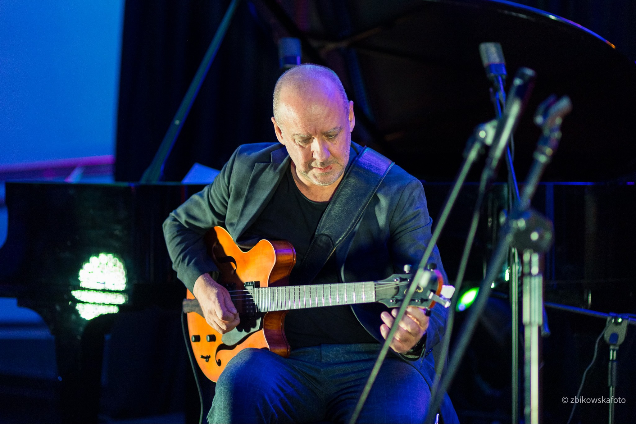 P&oacute;łmrok, mężczyzna gra na gitarze, siedzi na krześle