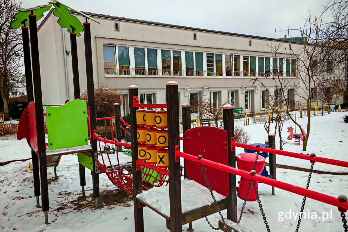 Urządzenie zabawowe na placu zabaw i widoczny w tle budynek przedszkola