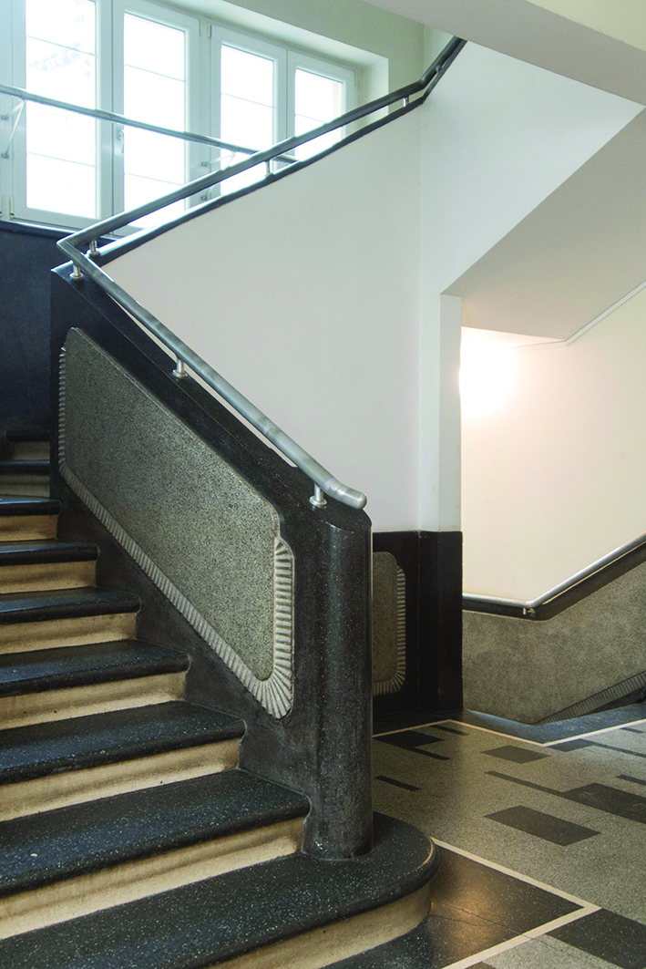 Balustrada murowana zwieńczona metalową poręczą. Klatka schodowa w&nbsp;kamienicy przy ul. Abrahama 28