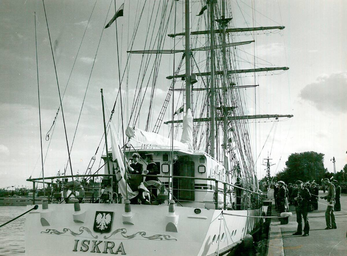 Czarno-białe zdjęcie ukazujące podniesienie bandery na rufie żaglowca ORP &bdquo;Iskra&rdquo;