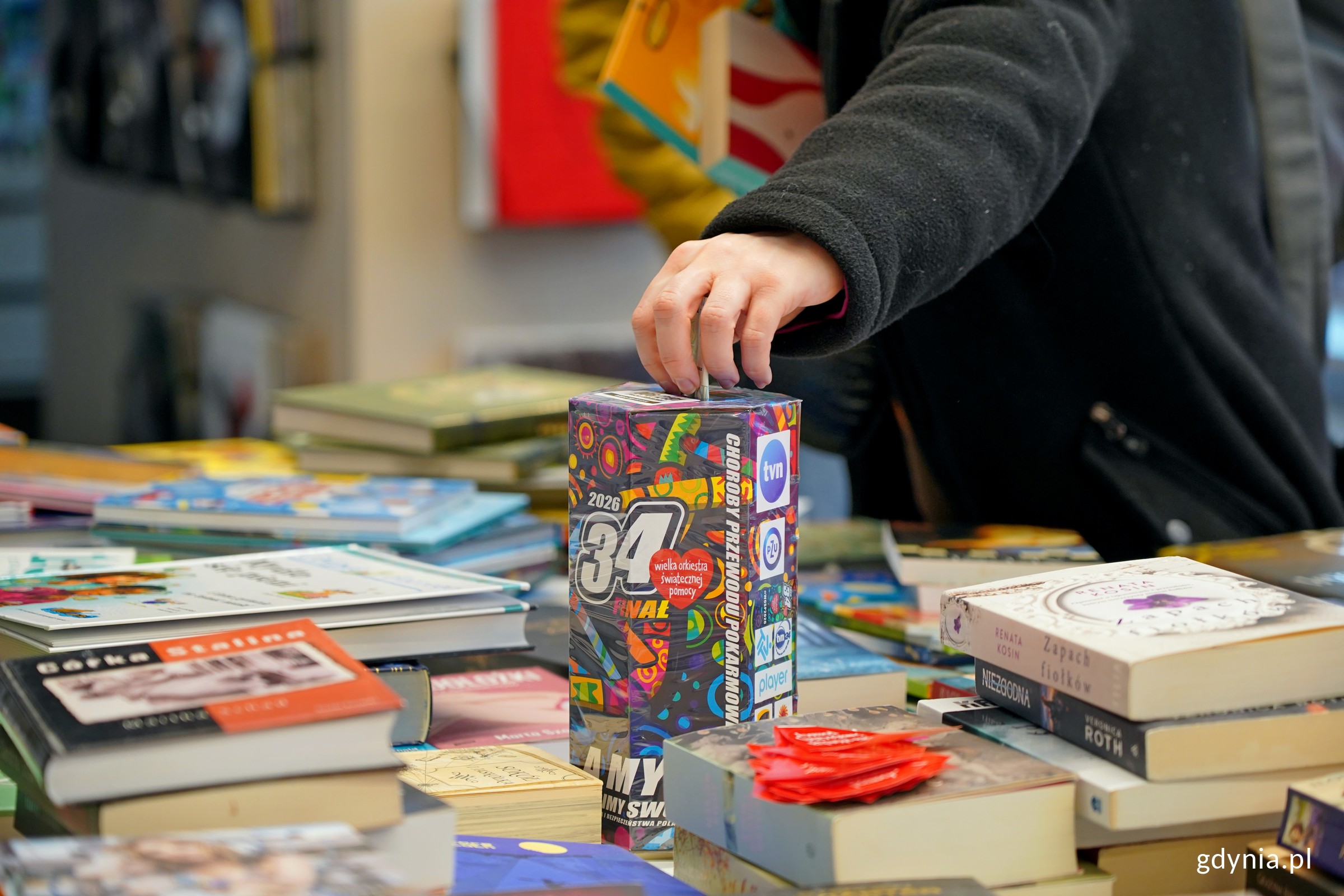 Puszka Wielkiej Orkiestry Świątecznej Pomocy wśr&oacute;d książek udostępnionych na charytatywny kiermasz (fot. Magdalena Czernek)