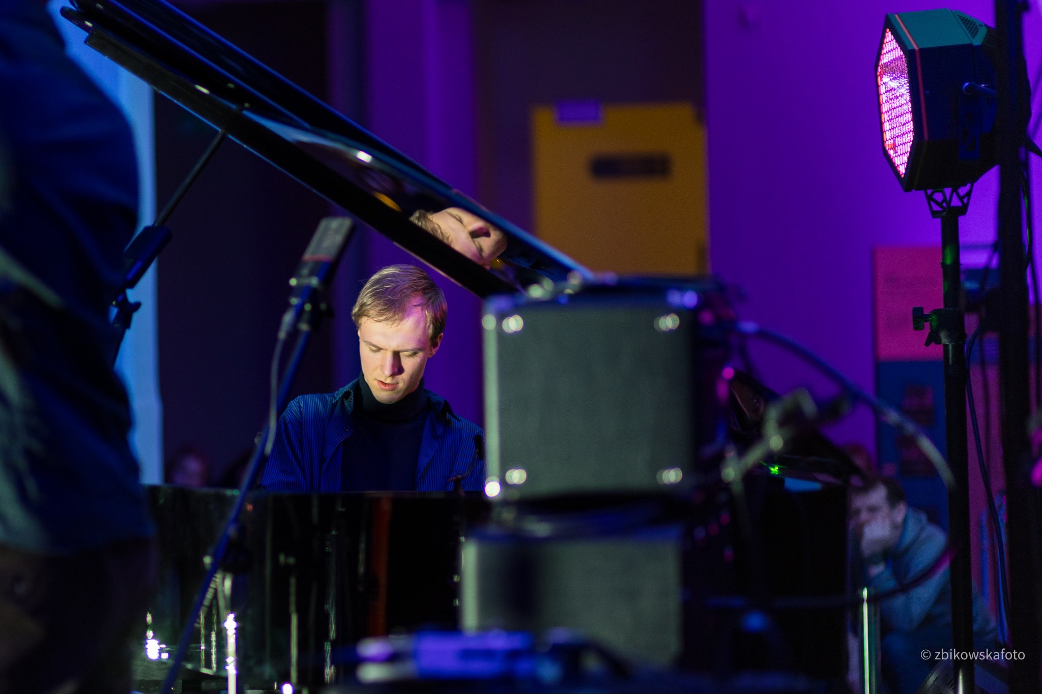 P&oacute;łmrok, wnętrze Muzeum Emigracji, fortepian, młody mężczyzna gra na fortepianie