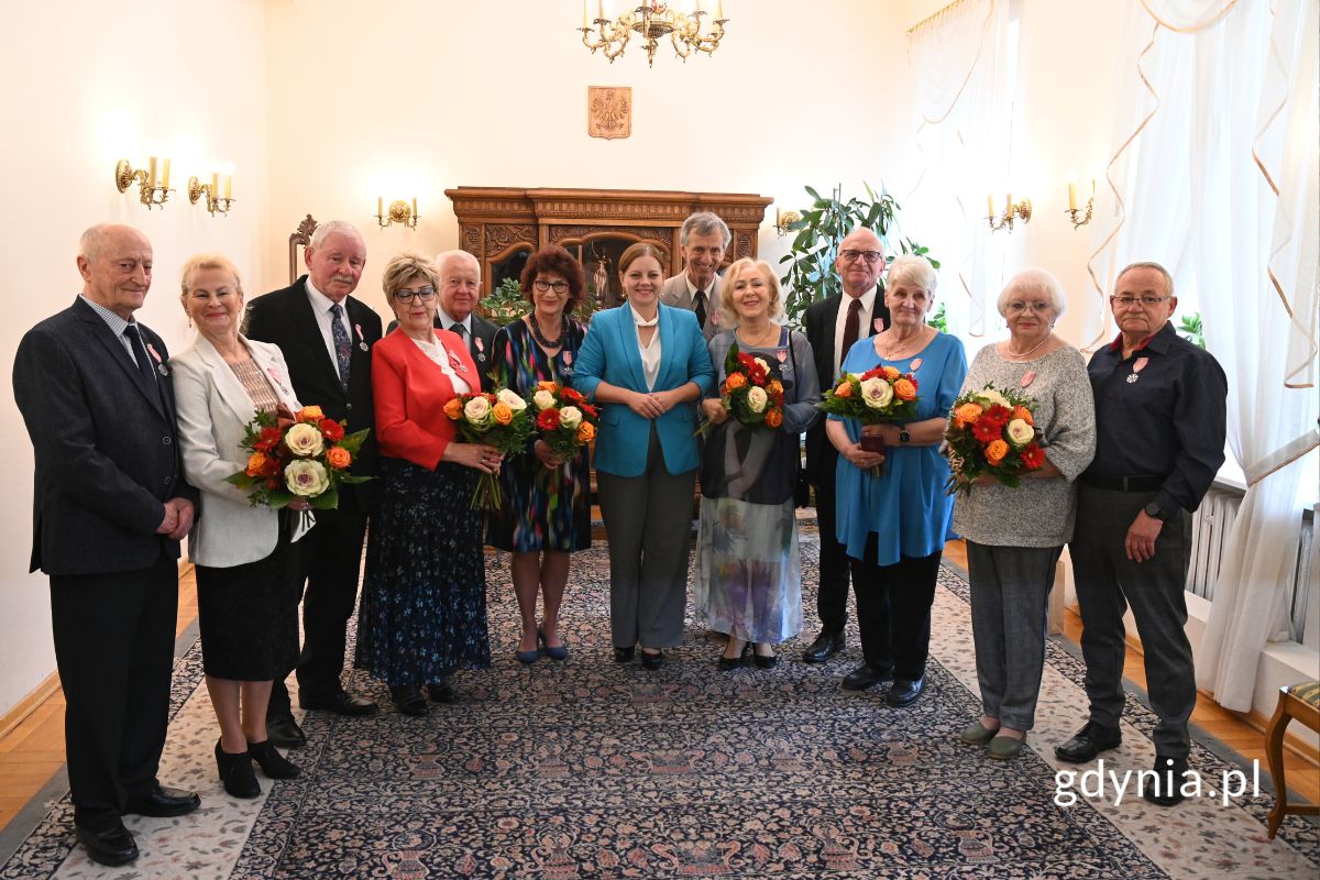 Grupa senior&oacute;w stojąca w rzędzie z prezydent Gdyni Aleksandrą Kosiorek