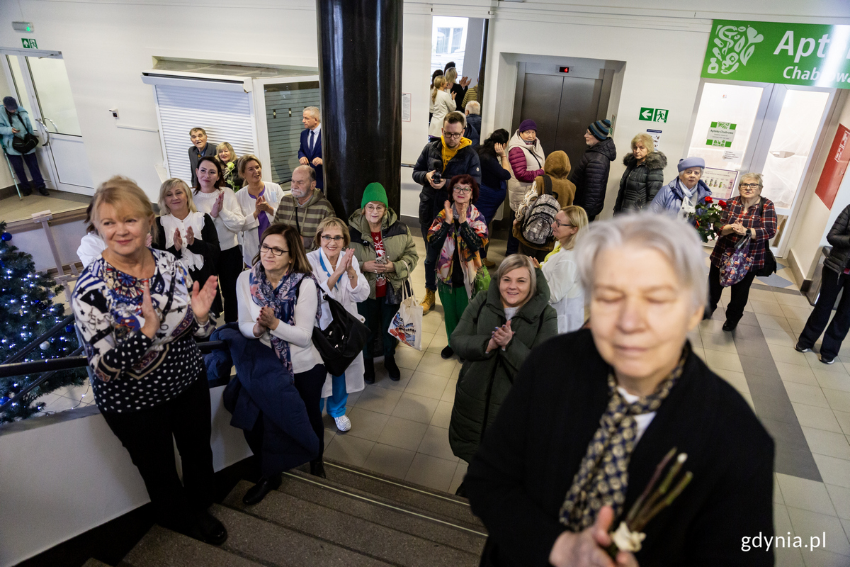Tłum ludzi na schodach przychodni bije brawo.