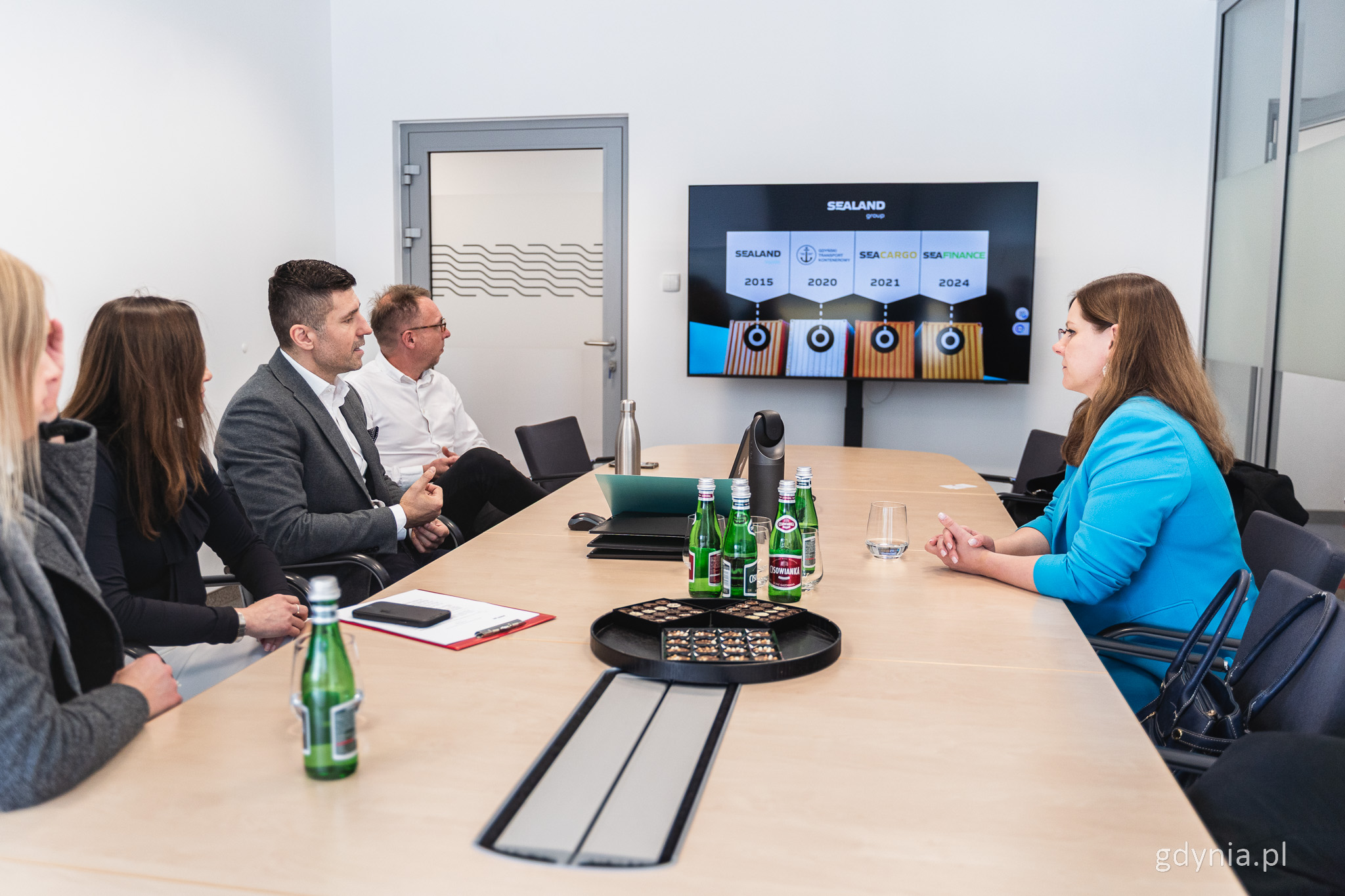 Sala konferencyjna, z prawej siedzi Aleksandra Kosiorek, z lewej przedstawciele firmy, na środku ekran z prezentacją
