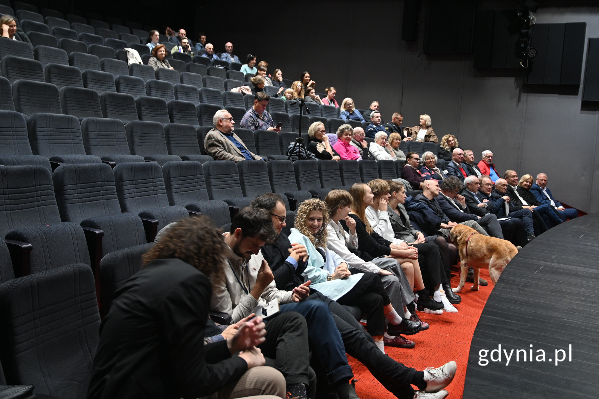 Osoby siedzące w szarej sali kinowej