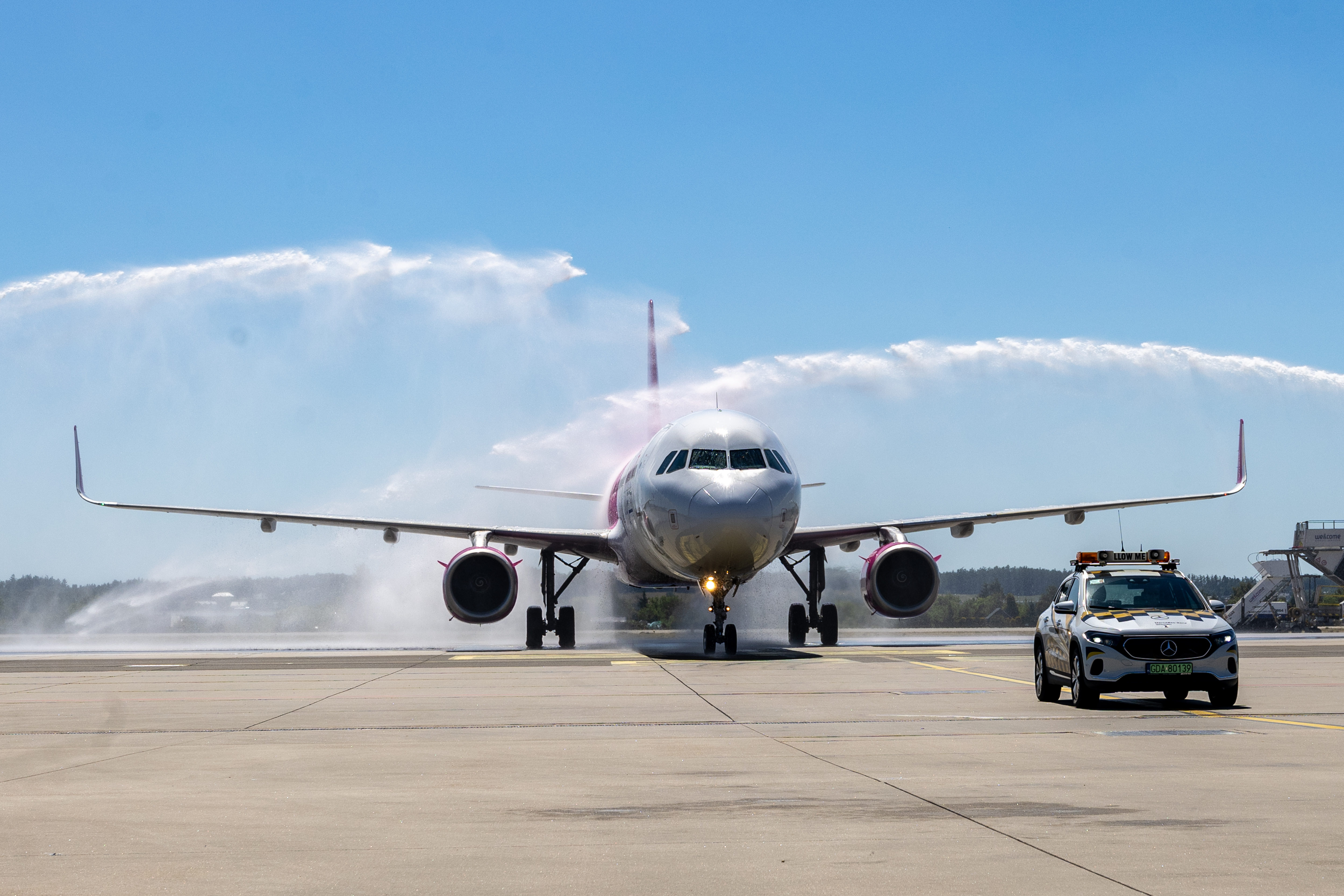 samolt na płycie lotniska oblewany wodą przez strażak&oacute;w 