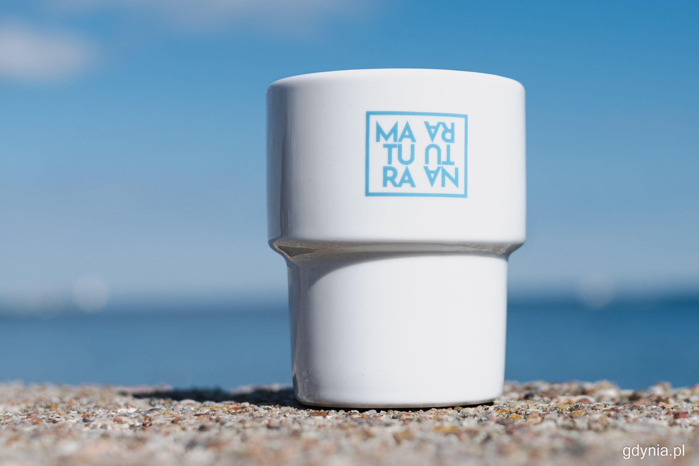 na zdjęciu biały kubek  na tle nieba