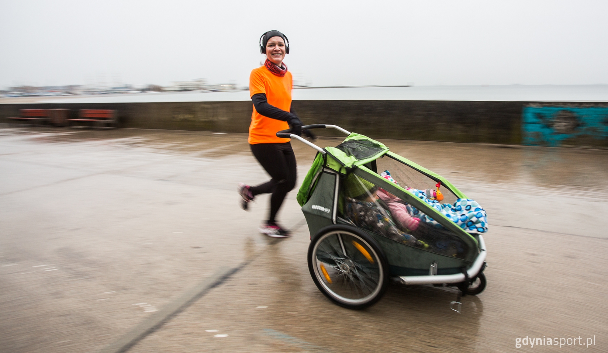 kobieta biegnąca z w&oacute;zkiem po bulwarze