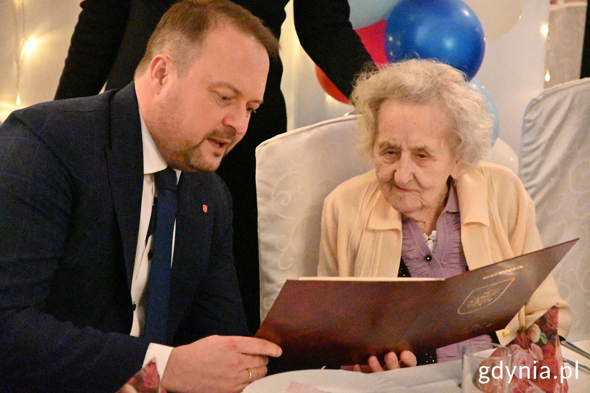 Wiceprezydent Gdyni Marek Łucyk (z lewej) czyta jubilatce pani R&oacute;ży Labuhn list gratulacyjny od prezydenta Wojciecha Szczurka