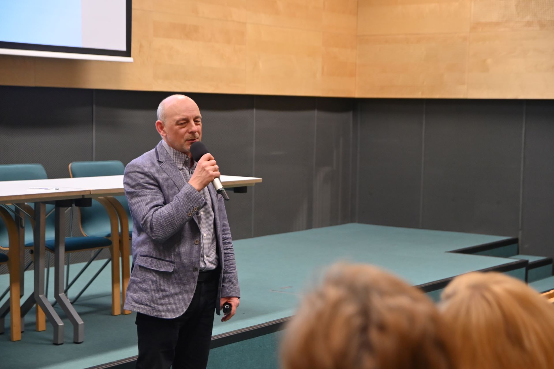 Mężczyzna w średnim wieku m&oacute;wiący do zgromadzonych specjalist&oacute;w