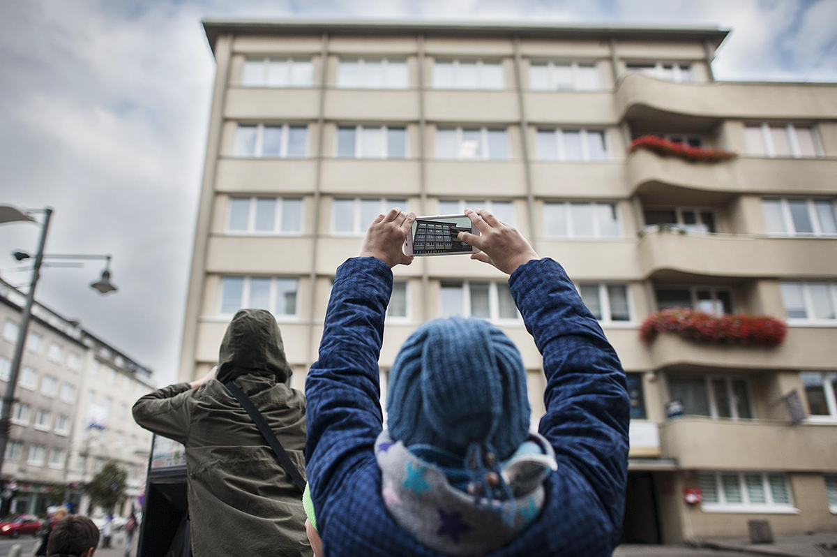 Człowiek fotografujący kamienicę. Źr&oacute;dło: Muzeum Miasta Gdyni
