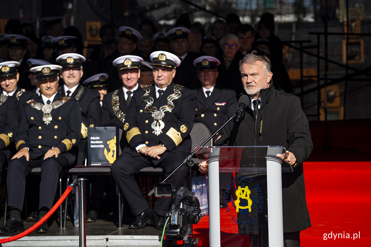 Na trybunie honorowej przemawia mężczyzna.