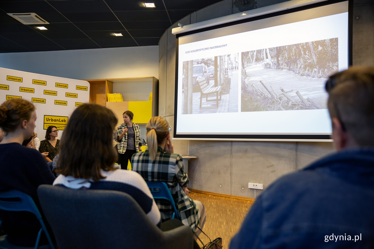 Ludzie w sali seminaryjnej ogladaja pokaz zdjęć na ekranie.