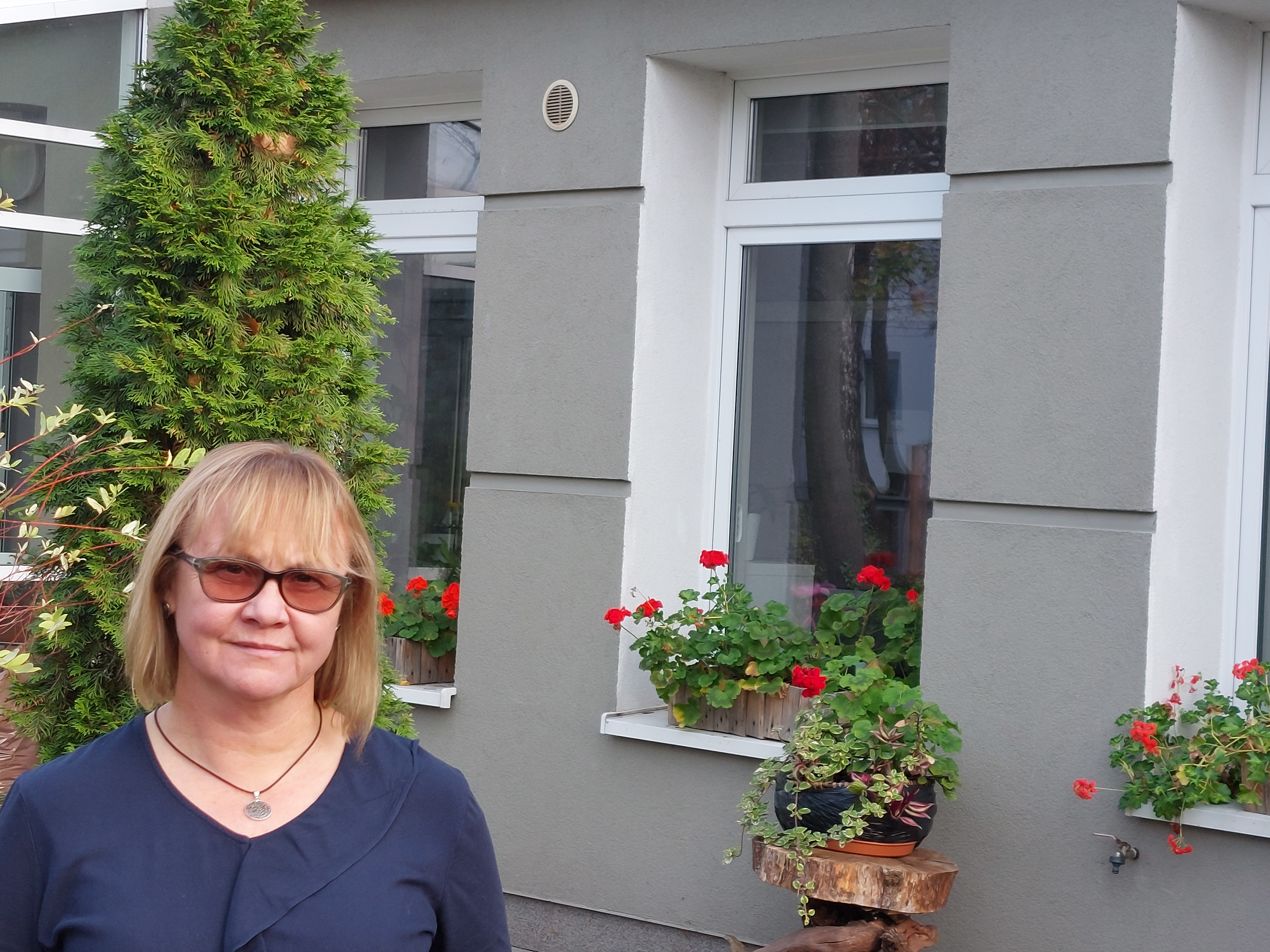 Kobieta w niebieskiej bluzce pozuje do zdjęcia