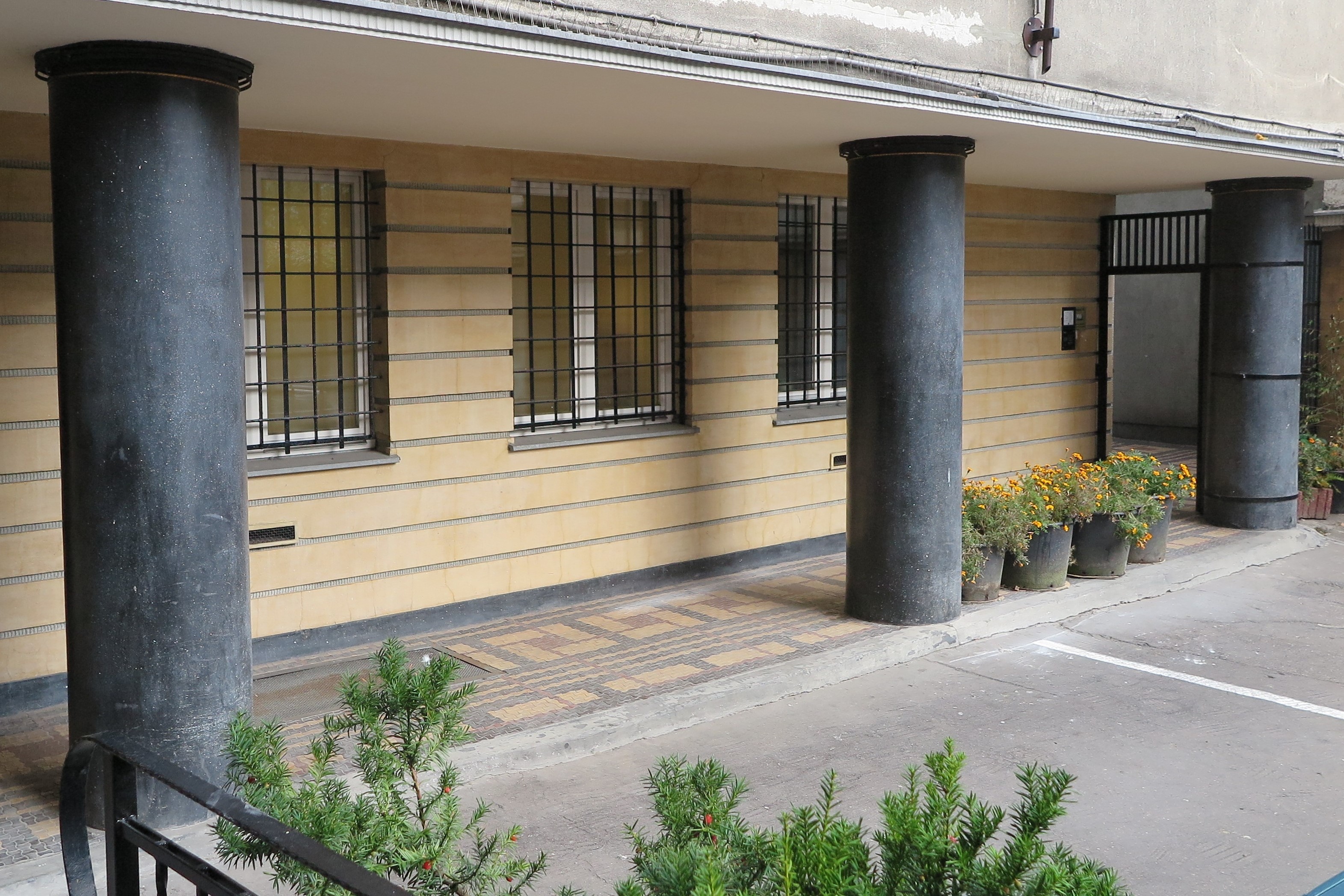 Wykończenie tynkarskie podcienia w budynku przy ul. 3 Maja 27-31 z tynkami szlifowanymi imitującymi kamień &ndash; ż&oacute;łtym na ścianie i czarnym na kolumnach. Jeden z najlepszych w Gdyni przykład&oacute;w rzemiosła budowlanego z lat 30. XX w. 