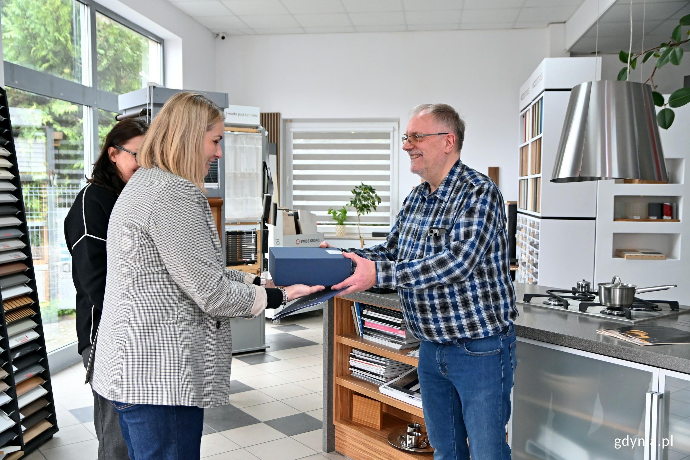 Przedstawicielki Gdyńskiego Centrum Wspierania Przedsiębiorczości wręczają list gratulacyjny od prezydent Gdyni i prezent Włodzimierzowi Czujowi, właścicielowi firmy Okland (fot. Magdalena Czernek)