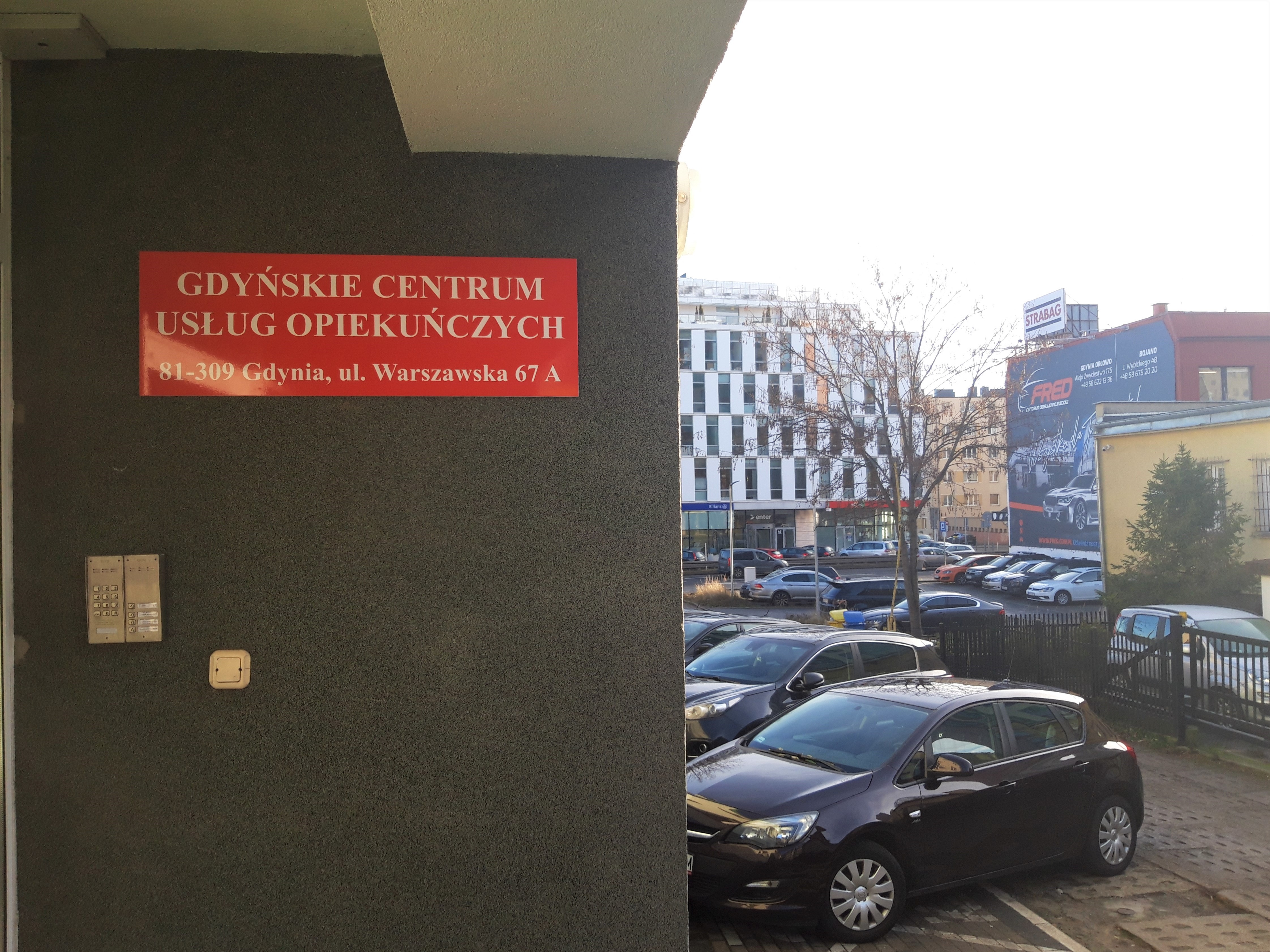 Czerwona tabliczka wisi na budynku w tle parking samochodowy