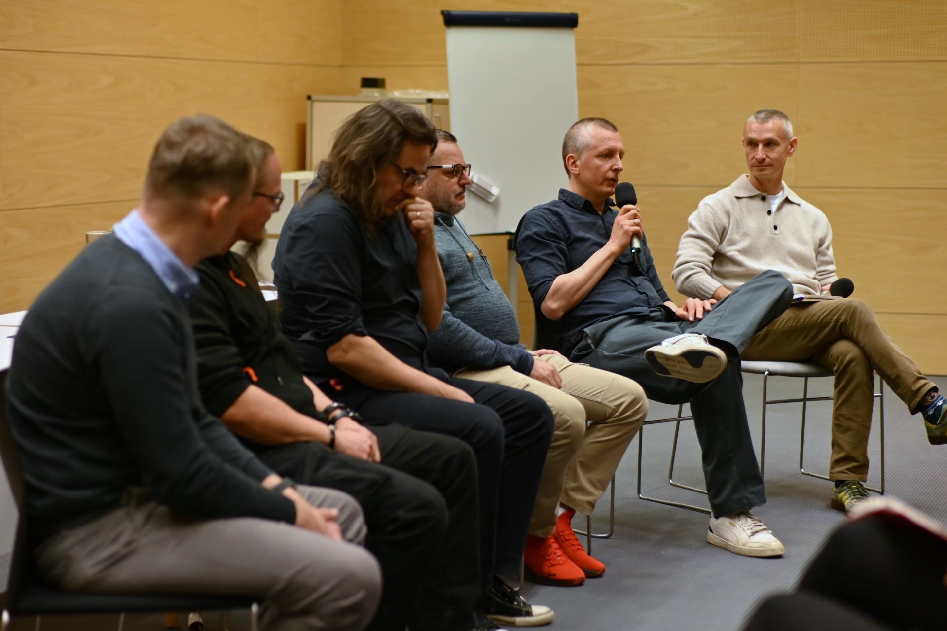 grupa siedzących mężczyzn prowadzących dyskusję. 