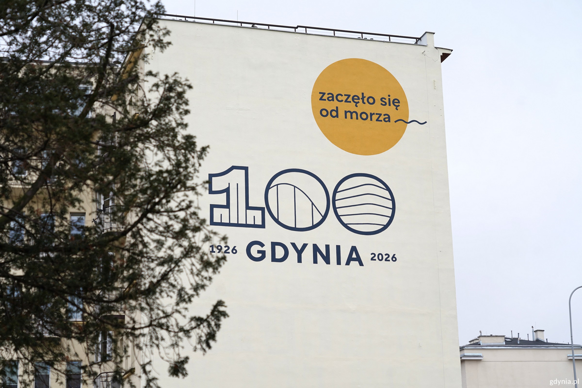 Napis na szczytowej ścianie budynku przy ul. 10 Lutego 5: 100 Gdynia, 1926-2026, zaczęło się od morza