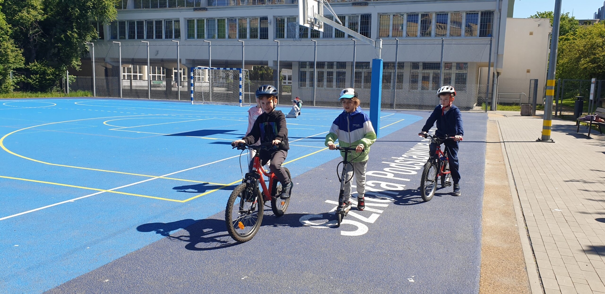 uczniowie na hulajnogach na boisku szkolnym