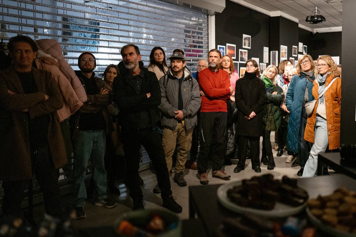 Grupa os&oacute;b stojąca w sali i słuchająca w ciszy prelekcji