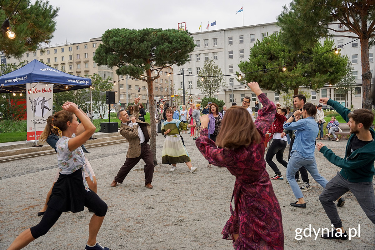 Park Centralny, plac między drzewami, ludzie tańczą, w tle namioty, budynki, oświetlenie